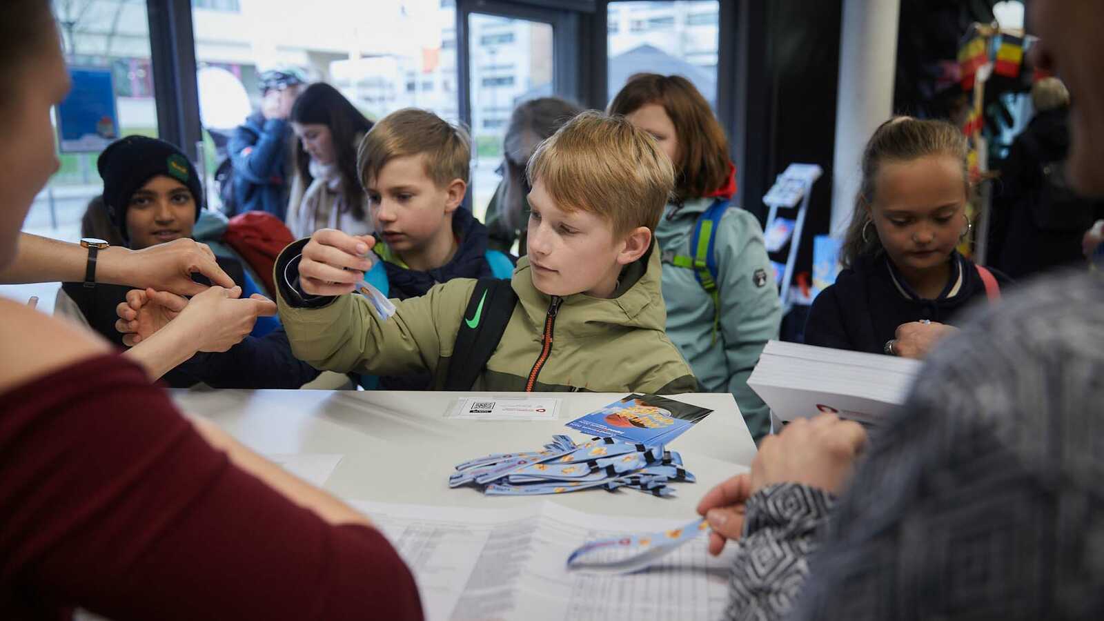 Eine Gruppe von Jungforschenden erhält ihre Veranstaltungsbändchen