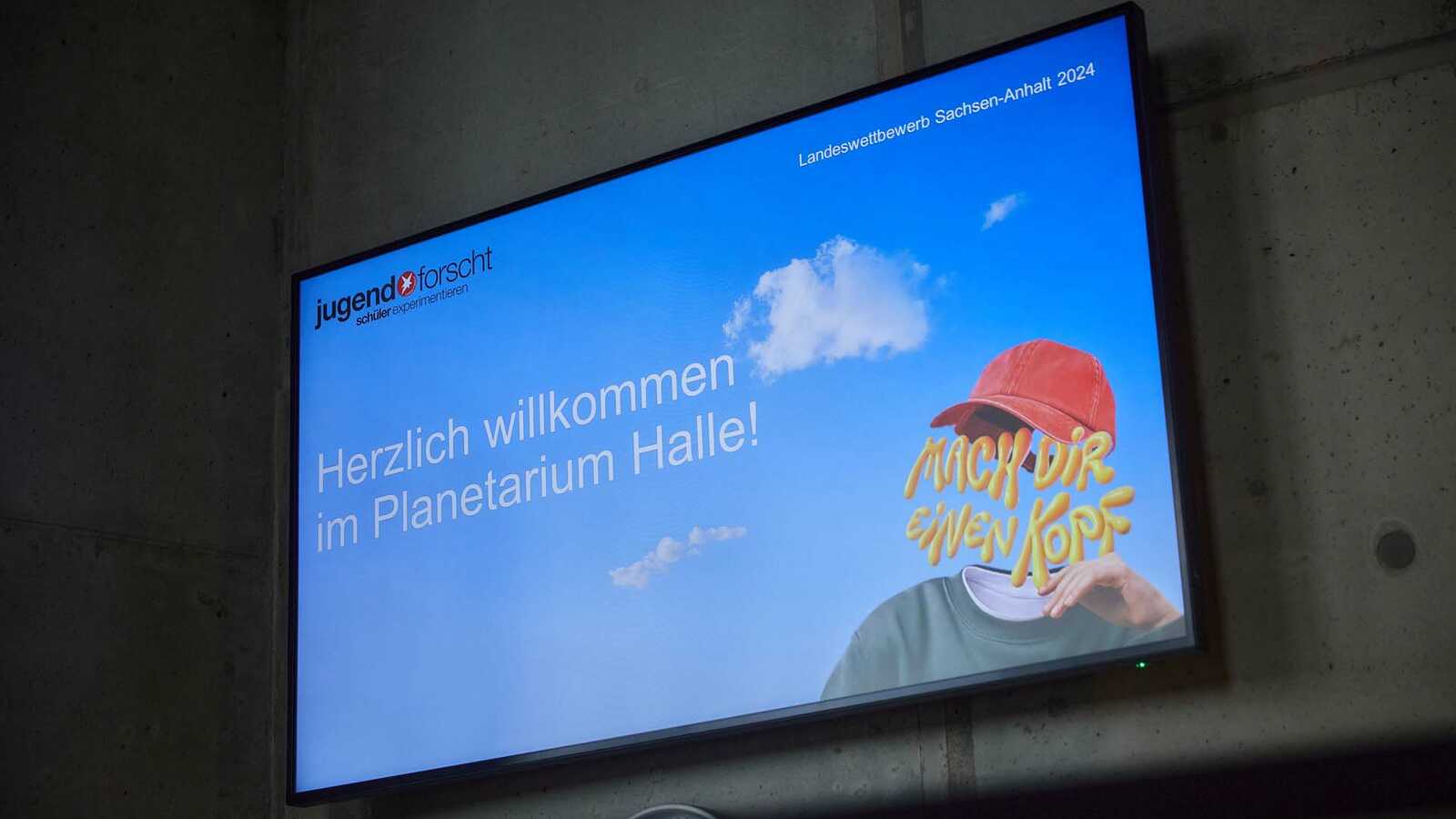 Auf einem Monitor steht "Herzlich Willkommen im Planetarium Halle"