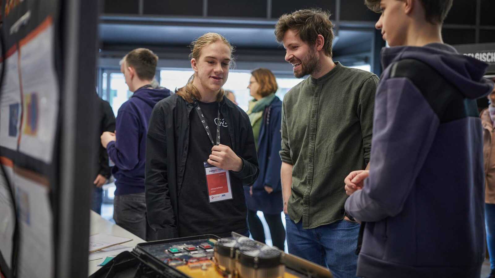 Menschen und Jungforschende an Ständen der Ausstellung im Gespräch