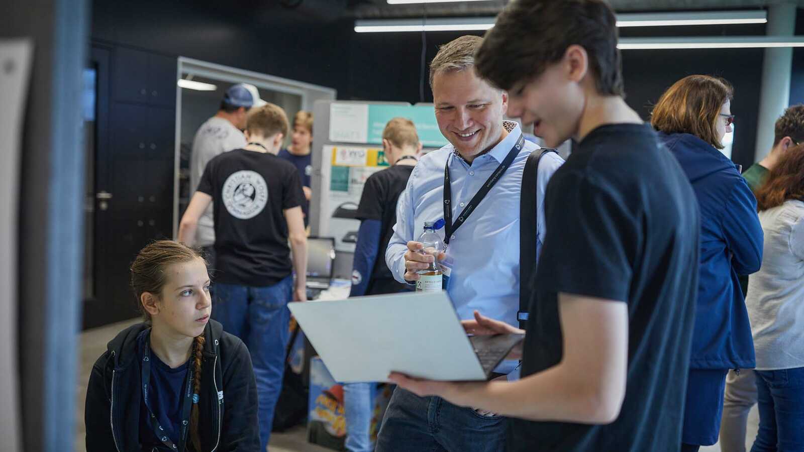 Menschen und Jungforschende an Ständen der Ausstellung im Gespräch