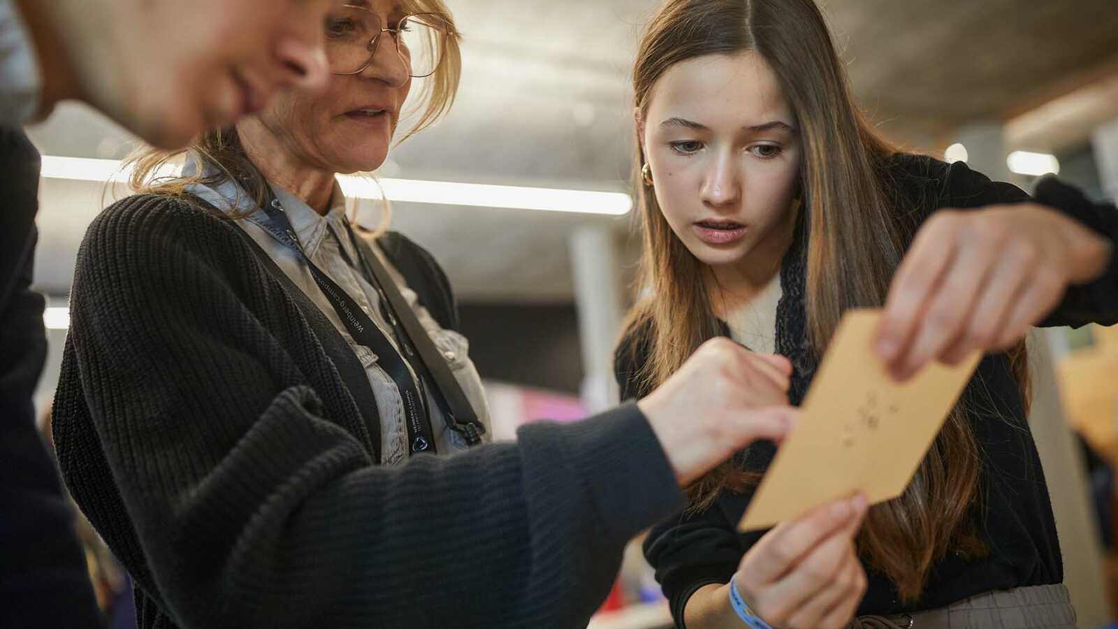 Menschen und Jungforschende an Ständen der Ausstellung im Gespräch