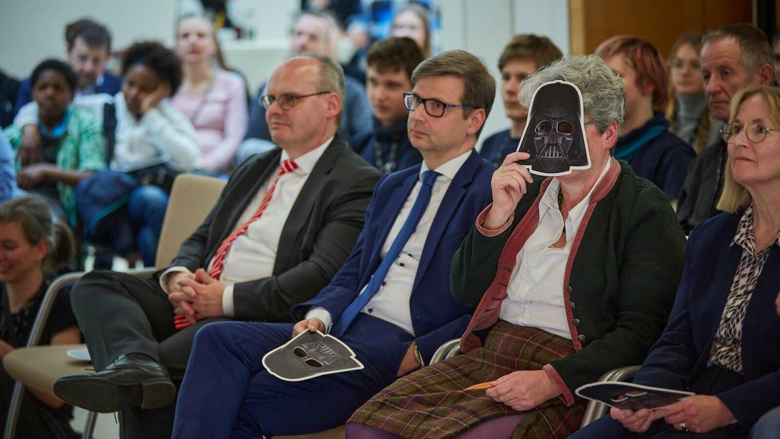 Menschen im Publikum mit Darth-Vader-Masken