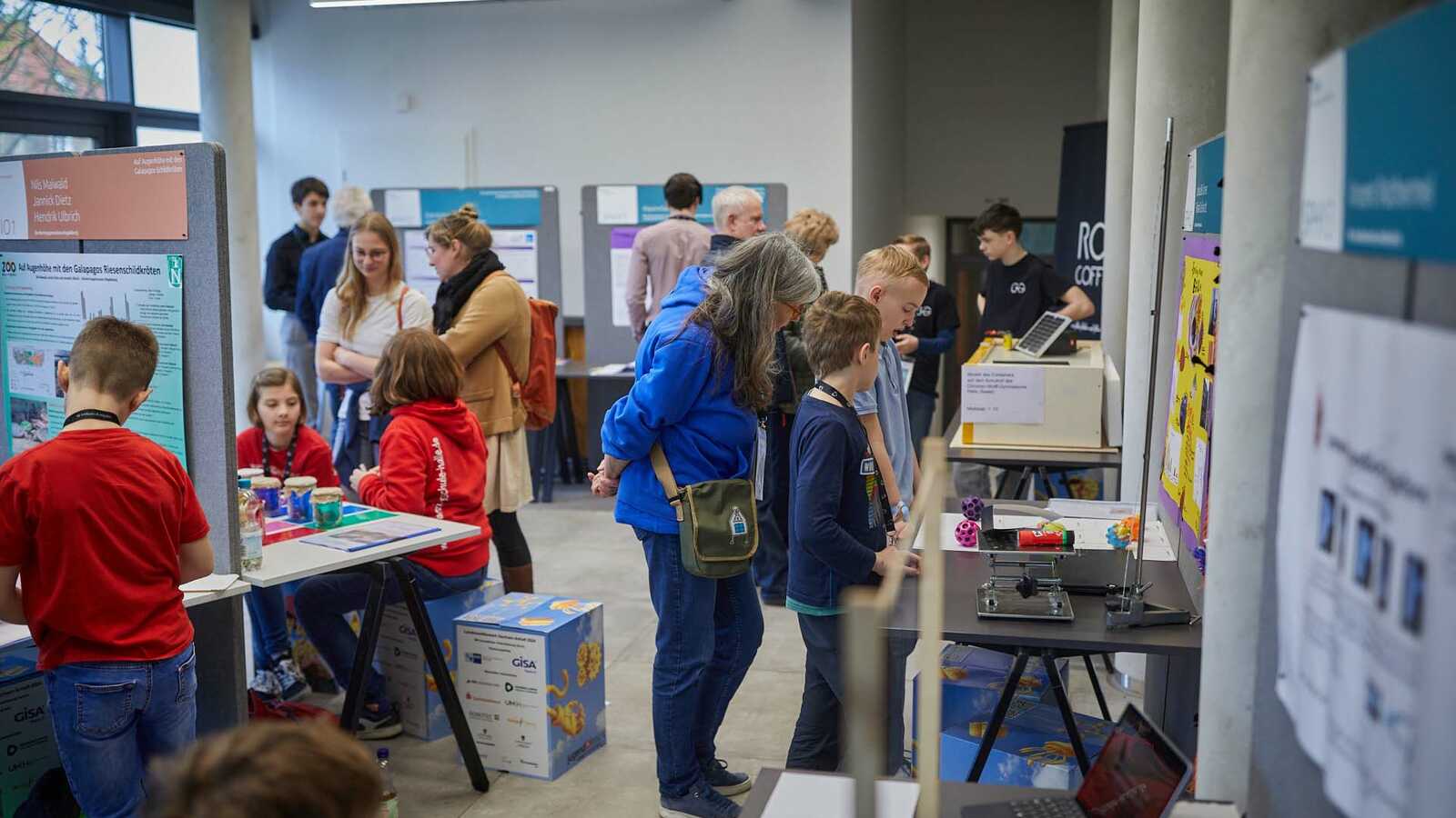 Menschen und Jungforschende an Ständen der Ausstellung im Gespräch