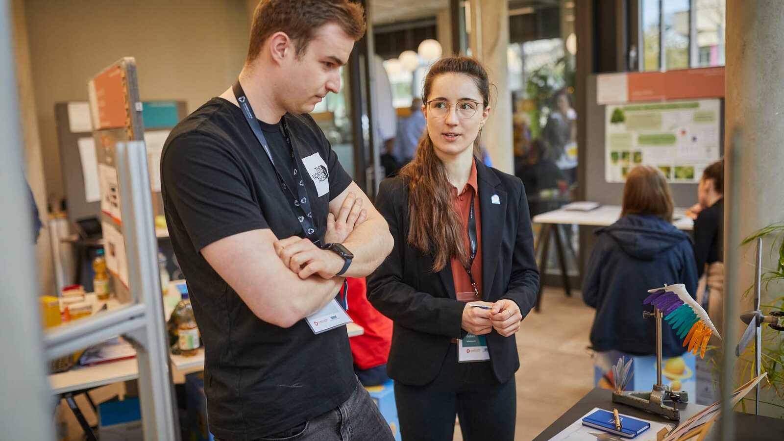 Menschen und Jungforschende an Ständen der Ausstellung im Gespräch