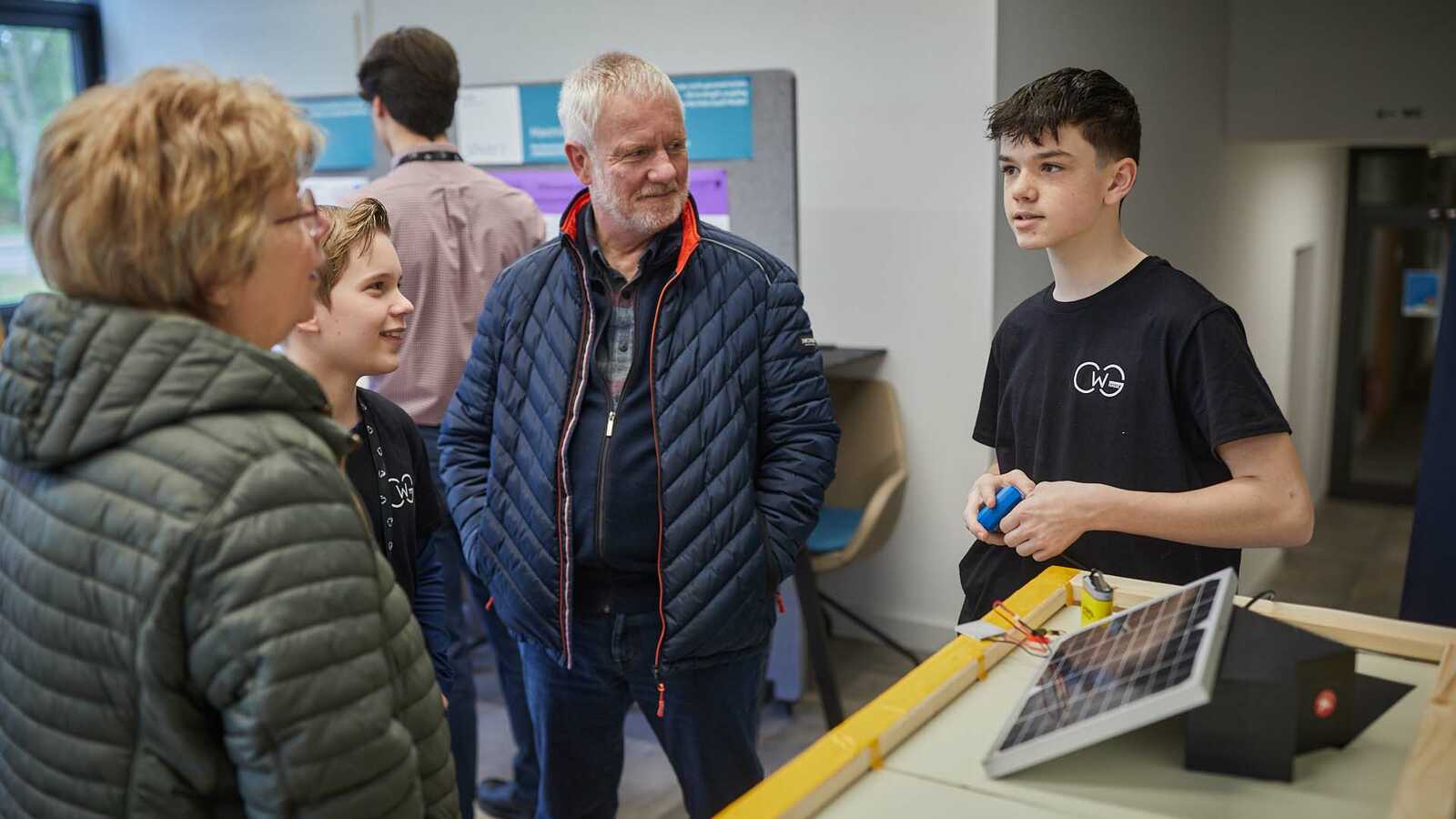 Menschen und Jungforschende an Ständen der Ausstellung im Gespräch