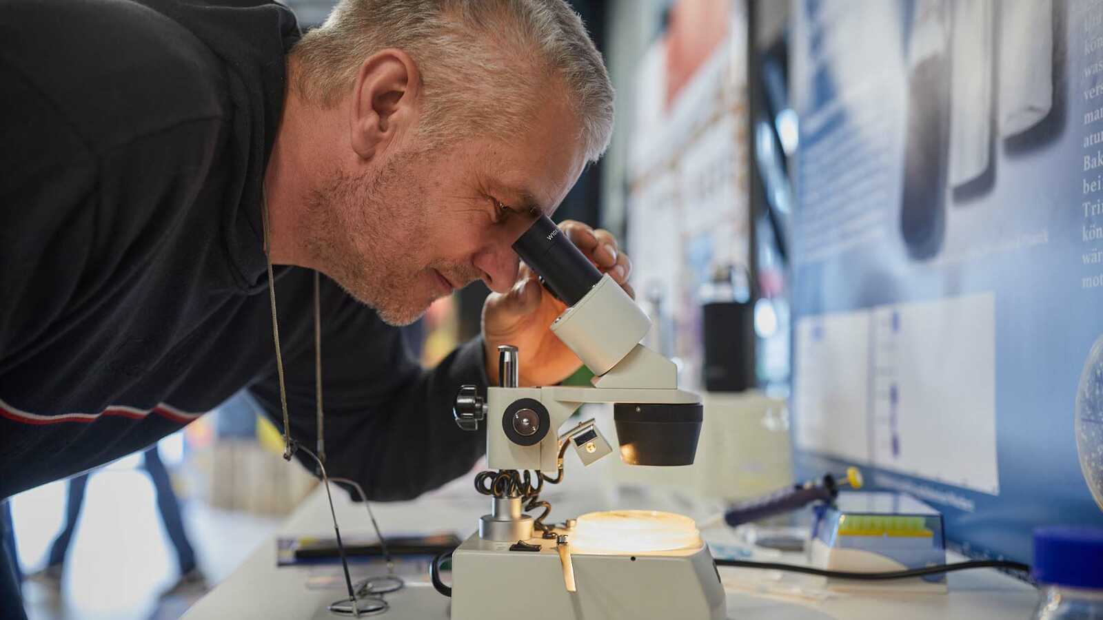 Mann mit Bart schaut in ein Mikroskop